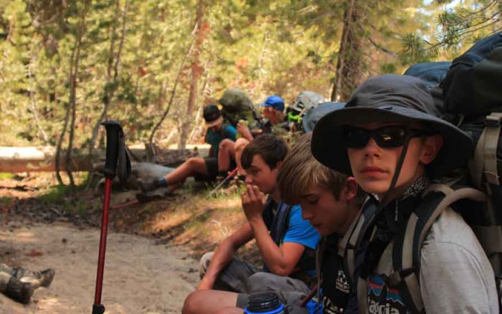 a group of boys take a break from backpacking on an outward bound course